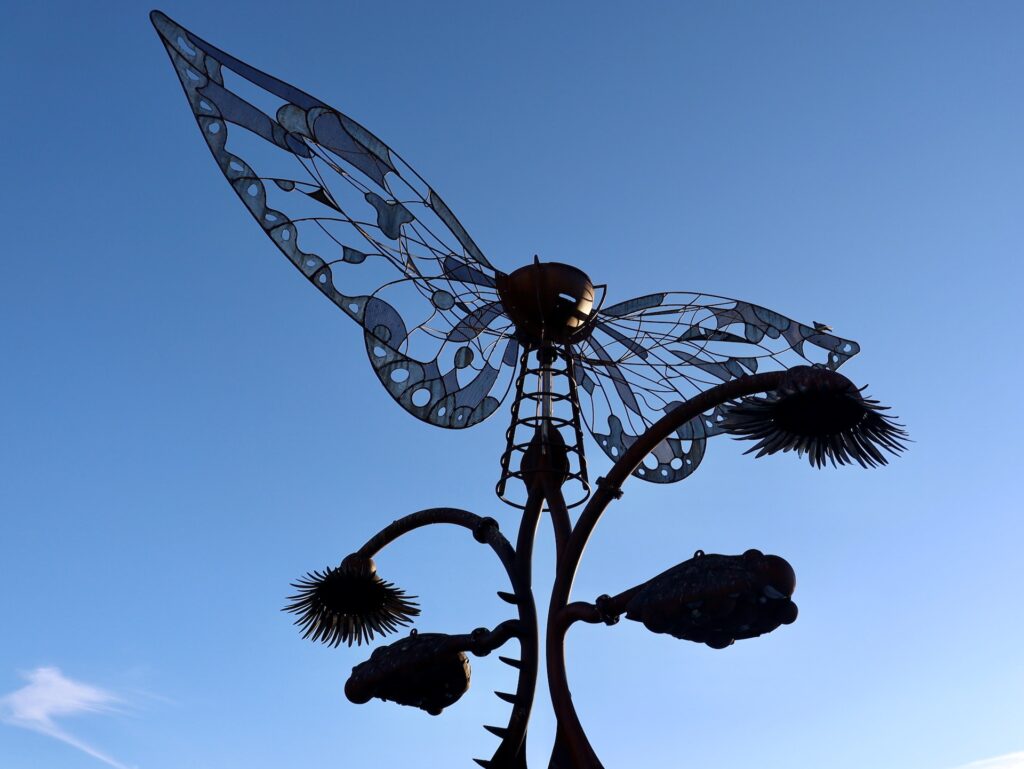 a metal sculpture from burning man displayed as public art in reno, photographed in silhouette against the blue sky