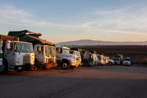 a fleet of WM trucks parked in the glow of sunrise