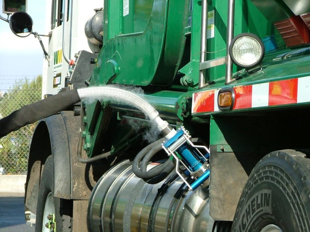 close up of a green WM garbage truck being filled with renewable landfill gas